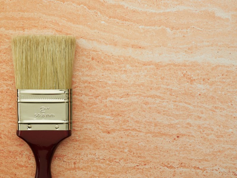 Brosse plate de peintre posée contre un mur fraîchement enduit